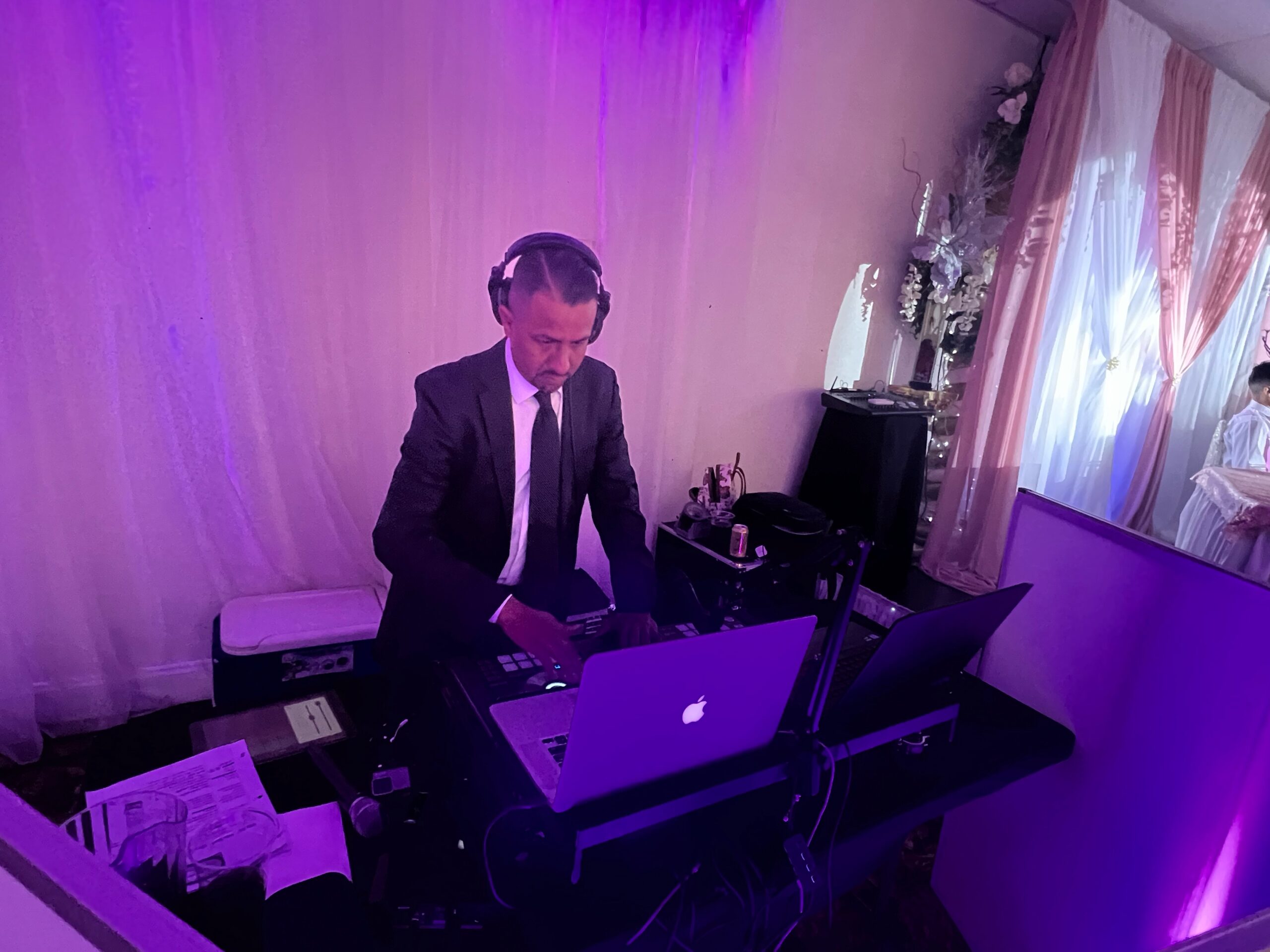 DJ who wears a headphone playing songs on a MacBook